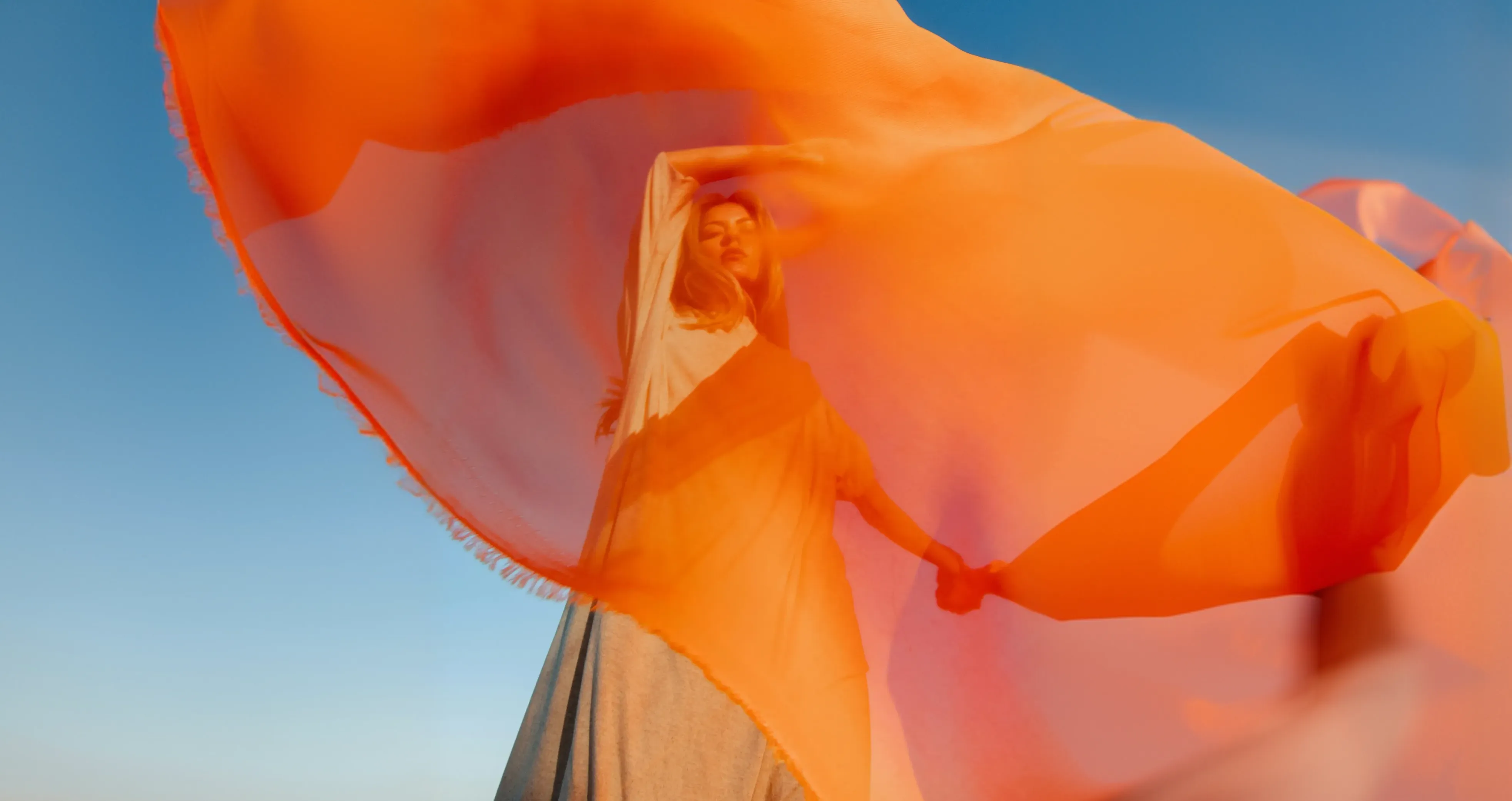 Eine Person mit einem orangefarbenen Tuch, das im Wind weht